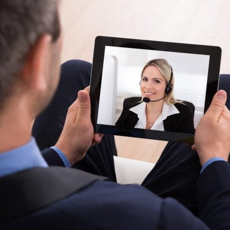 man holding a screen on which a woman appears by video conferencing